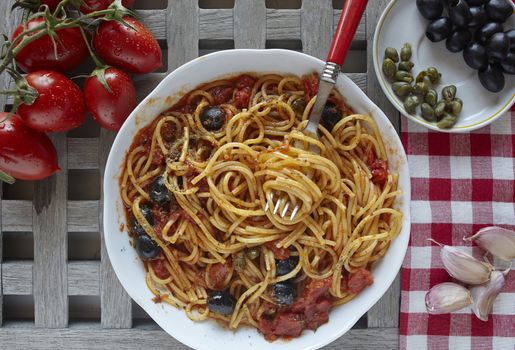 italian food: pasta with tomatoes, olives and capers, called puttanesca