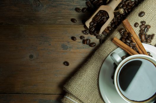 Hot coffee in a cup on top of a wooden background with copy space