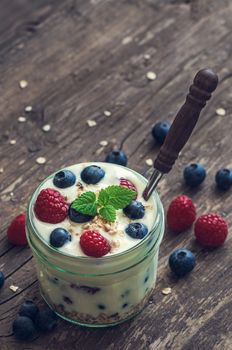 Serving of Yogurt with Whole Fresh Blueberries, Raspberries and Oatmeal on Old Rustic Wooden Table with Copyspace. Vintage Effect