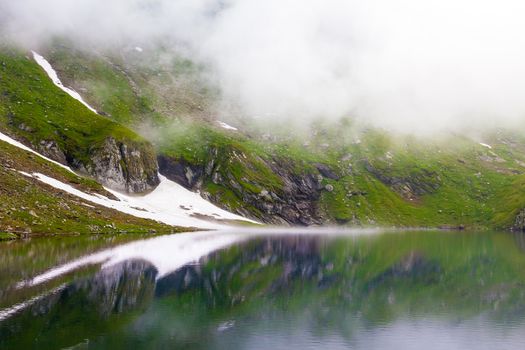 Idyllic view with snow on Balea Lake shore in Fagaras Mountains, Romania.