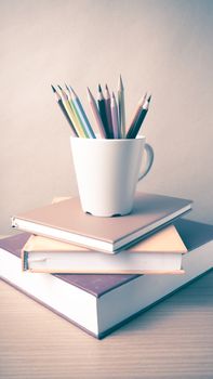 stack of book with color pencil on wood table background vintage style