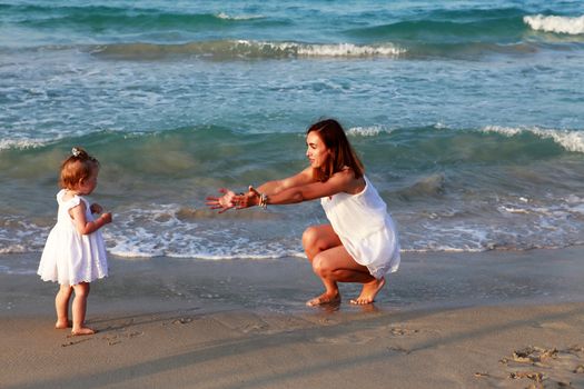 Happy mother holding her daughter on the beach