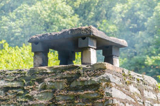 Old brick chimney with stone slabs cover.