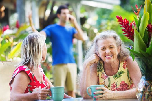 Cringing woman and friend near loud man on cellphone