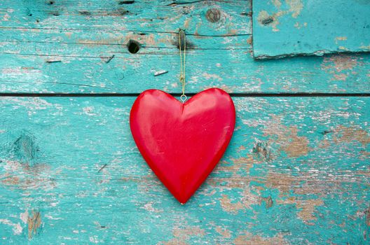 hang red wooden heart symbol on old grunge green house wall