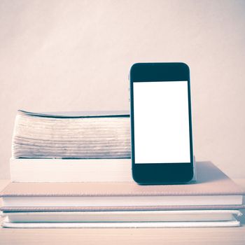 stack of book and smart phone on wood background vintage style