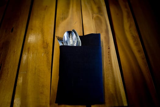 fork and spoon in dark blue cloth,on wooden table background