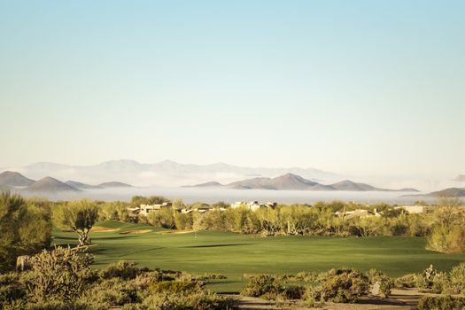 Scottsdale, Phoenix area golf course with dramatic unusual low lying fog in below mountain peaks in distance