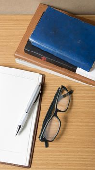 open notebook with stack of book on wood background