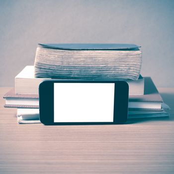 stack of book and smart phone on wood background vintage style