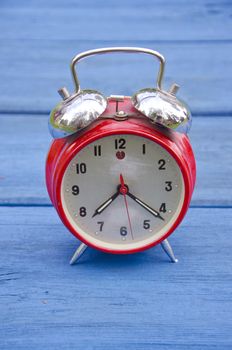 red old style alarm clock on blue wooden garden table