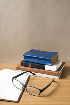 open notebook with stack of book on wood background