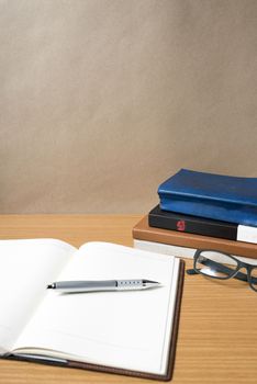 open notebook with stack of book on wood background