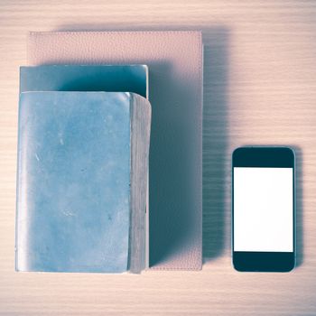 stack of book and smart phone on wood background vintage style