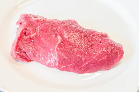 Fresh raw beef steak on a white plate.