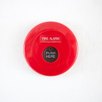 Fire alarm on a white concrete wall .