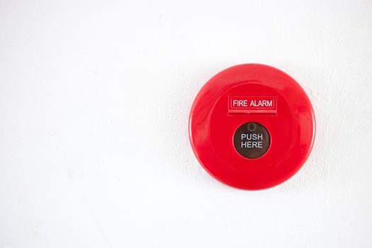 Fire alarm on a white concrete wall .