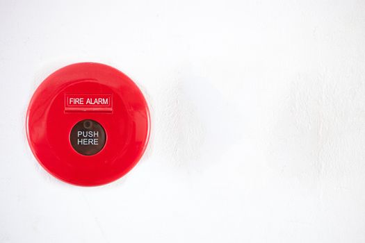 Fire alarm on a white concrete wall .