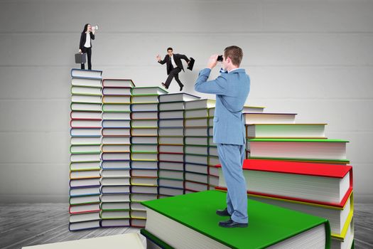 Businessman looking through binoculars against steps made out of books