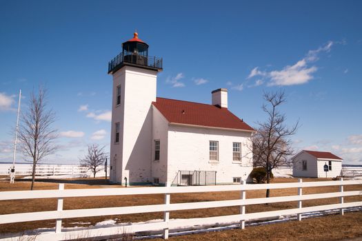 A historic light stand looking over a still frozen Lake Michigan with spring approaching