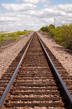 Railroad tracks lead off into the distance under a beautiful Teaxs Sky