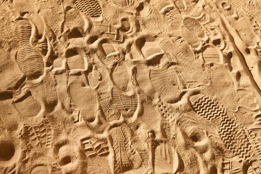 prints from various footwear on sand, background