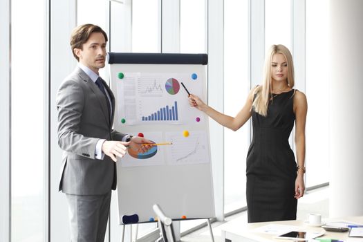 Workers at business meeting looking at presentation of financial reports in modern office