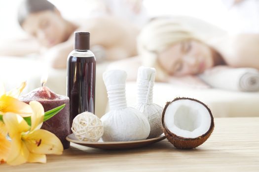 Spa massage tools and women getting massage on background