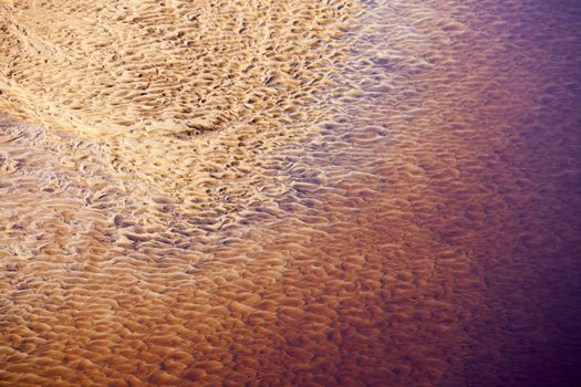 Wavy sand texture patterns on the bottom of the river in red
