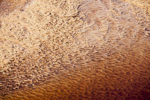 Wavy sand texture patterns on the bottom of the river in red