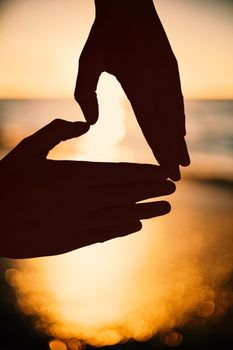 Woman making heart shape with hands against sunset of a beautiful day