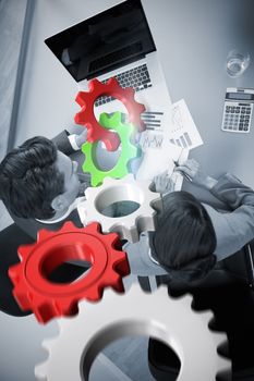 White and red cogs and wheels against sales persons studying statistics