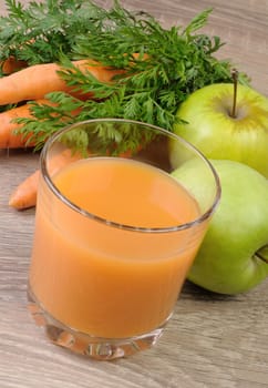 glass of apple-carrot juice on the table with carrots and apples