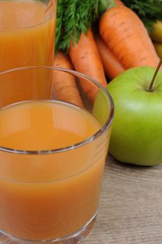 glass of apple-carrot juice on the table with carrots and apples