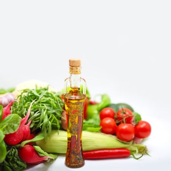 Pile of assorted vegetables and cooking oil on white background