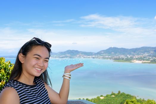 Women tourist smiling are happy to show his hand inviting them to see the beautiful landscape of sea on Khao-Khad mountain viewpoint famous attractions in Phuket Province, Thailand