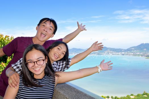 Family of tourists smiling are happy and show their hands invite to see the beautiful landscape of sea on Khao-Khad mountain viewpoint famous attractions in Phuket Province, Thailand