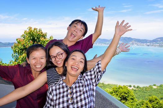 Family of tourists smiling are happy and show their hands invite to see the beautiful landscape of sea on Khao-Khad mountain viewpoint famous attractions in Phuket Province, Thailand