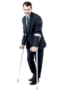 Confident businessman walking with crutches