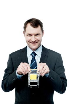 Happy businessman showing mini shopping cart