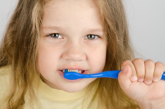 A girl of four years old brushing his teeth with a toothbrush