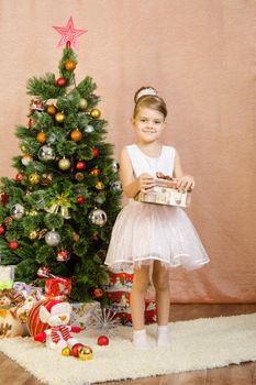 Five-year girl in a New Year's dress standing on a mat at the Christmas tree