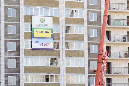 Unfinished multi-storey residential building with an advertising banner mortgage Sberbank, VTB24 on the facade