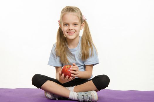 Six year old girl sitting Europeans holding an apple