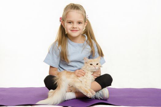 Six year old girl Europeans after exercise sitting on a rug with a domestic cat