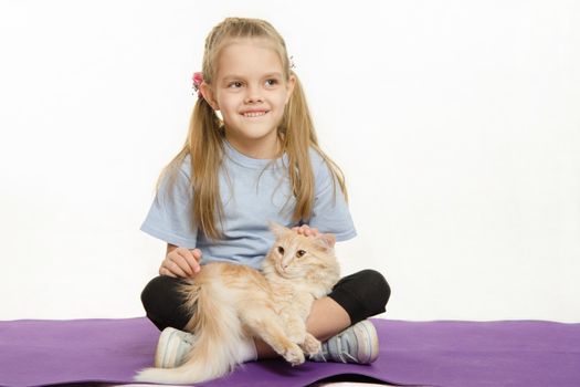 Six year old girl Europeans after exercise sitting on a rug with a domestic cat