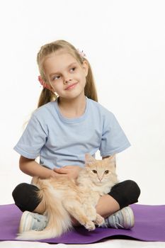 Six year old girl Europeans after exercise sitting on a rug with a domestic cat