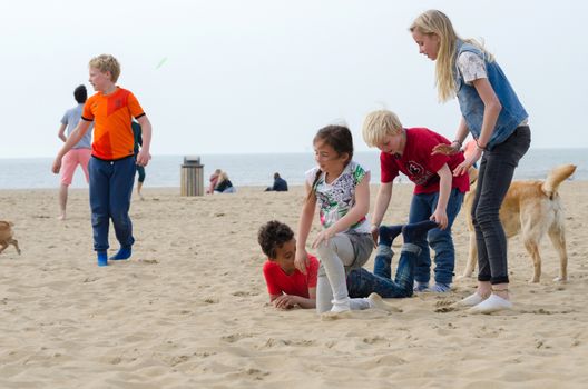 The Hague, Netherlands - May 8, 2015: Children playing at the beach, Scheveningen district in The Hague, Netherlands. Scheveningen is a modern seaside resort with a long sandy beach, an esplanade, a pier, and a lighthouse.