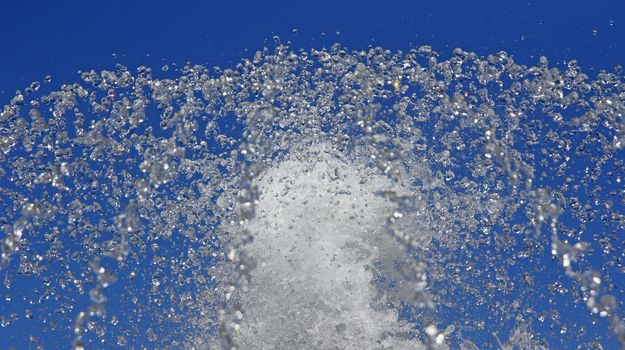 Fountain drops of pure water against a blue sky.