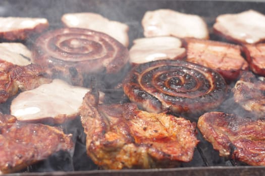 Barbecuing minced meat, traditional Romanian preparation for barbecue, called "mici",  on charcoal fire - closeup image.
